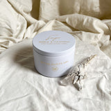 Sage candle with gold text on a textured beige fabric background