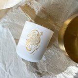White candle with gold design on a textured surface