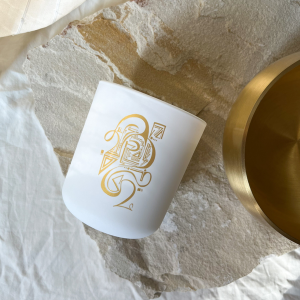 White candle with gold design on a textured surface